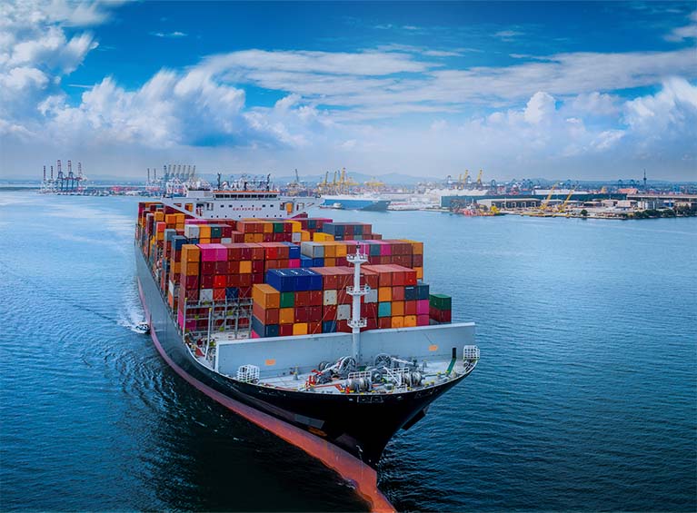 An above view of a cargo ship in motion on the ocean carrying Delmar shipping containers.